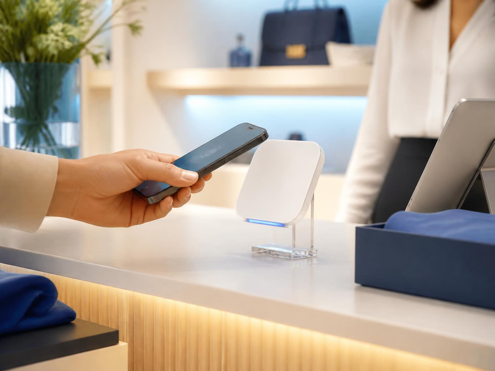 A customer holding a smartphone next to a ReviewTAP card on a shop counter